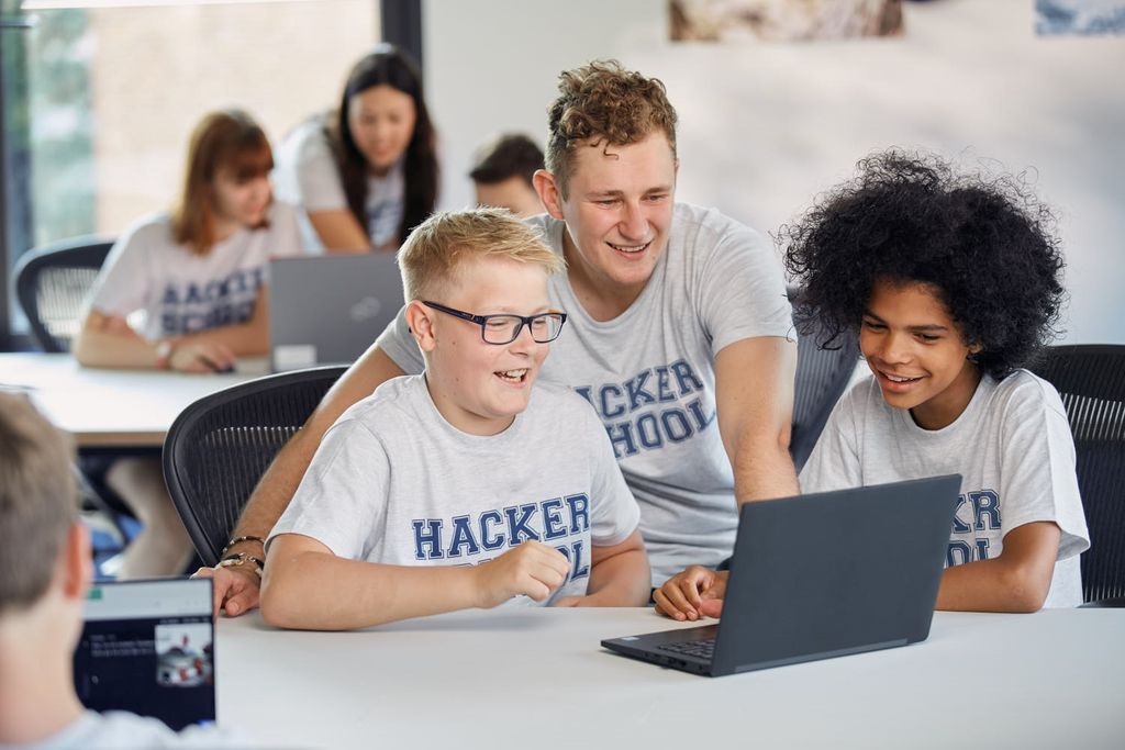 Ein Lehrer der Hacker School bringt zwei Kindern das Programmieren bei.